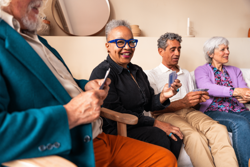 Four seniors playing cards and laughing on a couch