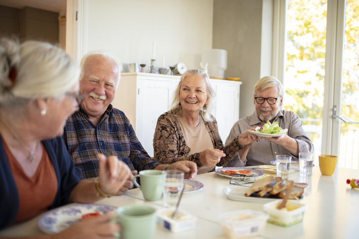 Four seniors enjoying a meal at a bright table