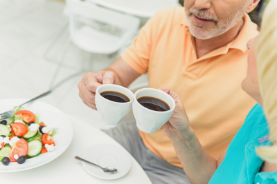 Two seniors clinking coffee cups