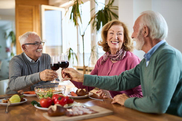 Three seniors toasting with wine at dinner