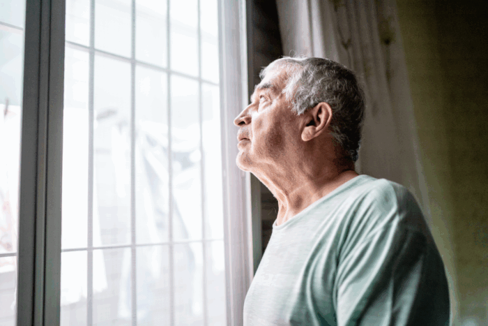 senior man looking out a window