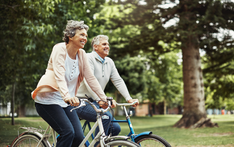 Senior woman smiling while enjoying a bike ride on a path in a park