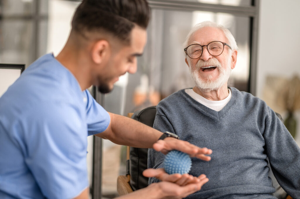 Physical therapist helping senior with ball