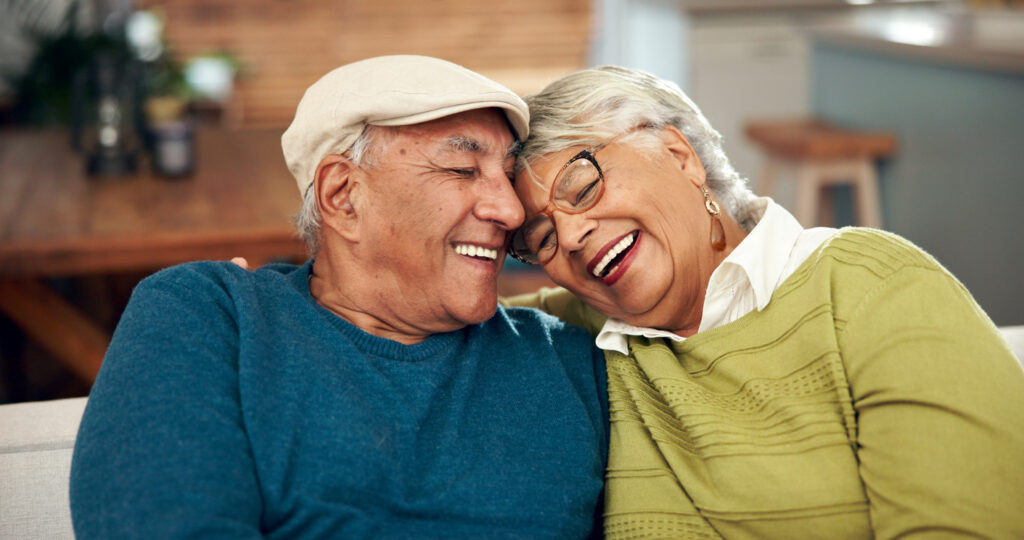 Happy, mature couple and hug with love on sofa for bonding, support and embrace for relationship memory. Smile, woman and man with trust, care and relax together on couch of retirement peace at home