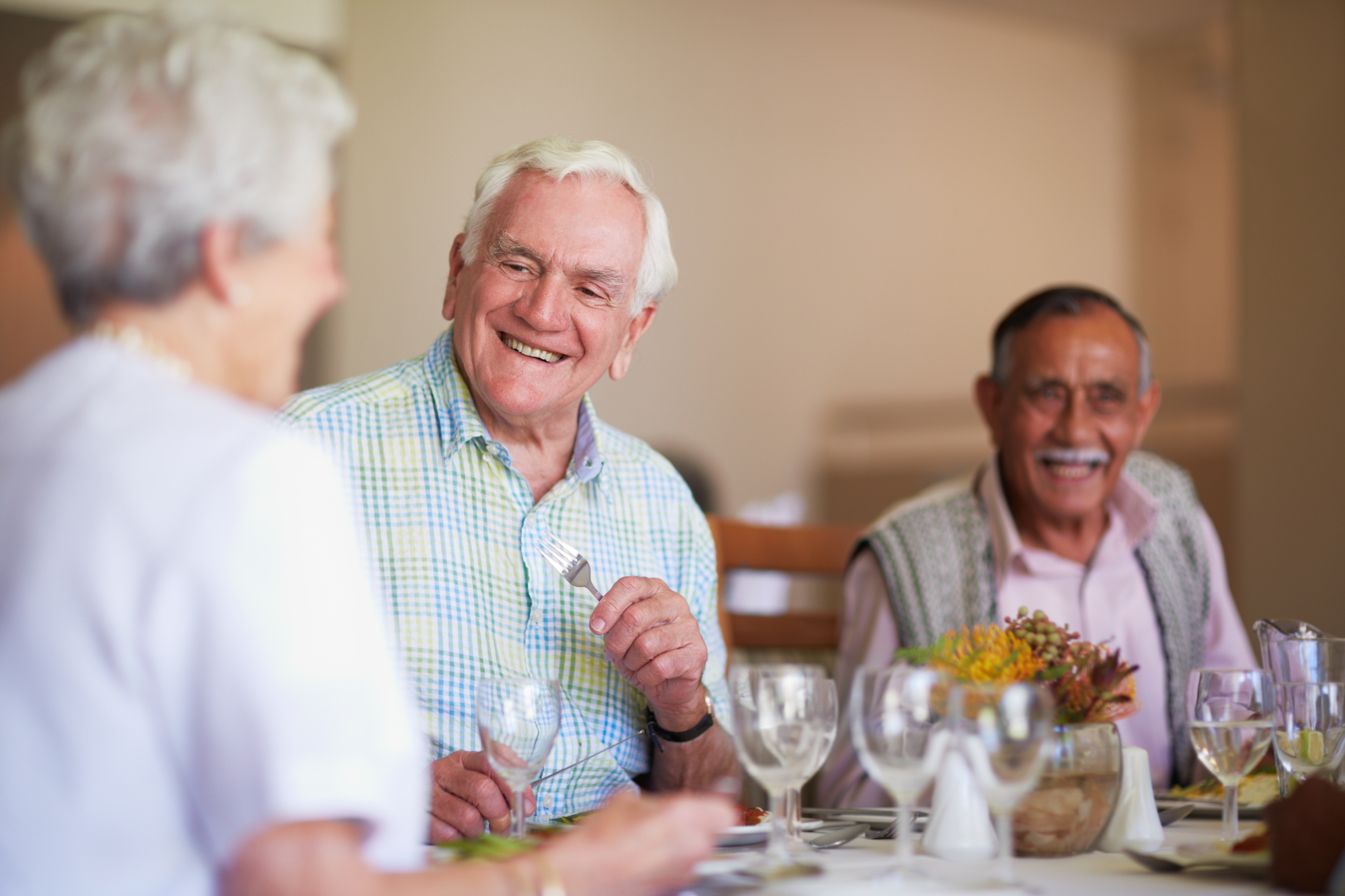 Seniors sitting at a table laughing and enjoying food at National Church Residences